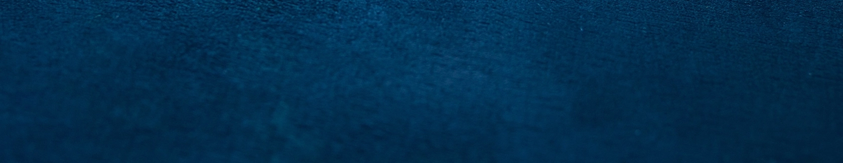 Deep blue textured fabric background, evoking a calm and serene atmosphere. The surface appears soft with subtle shading and no distinct patterns.