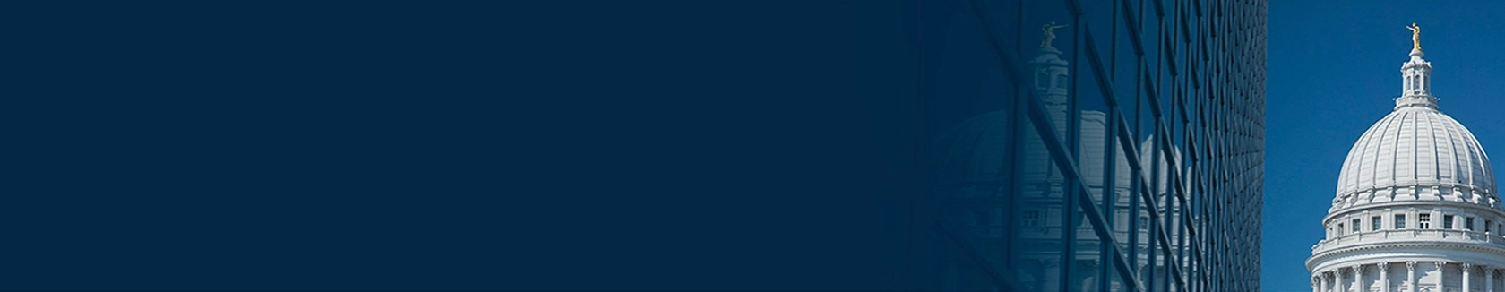 The U.S. Capitol against a dark blue background. The dome is reflected on a glass building.